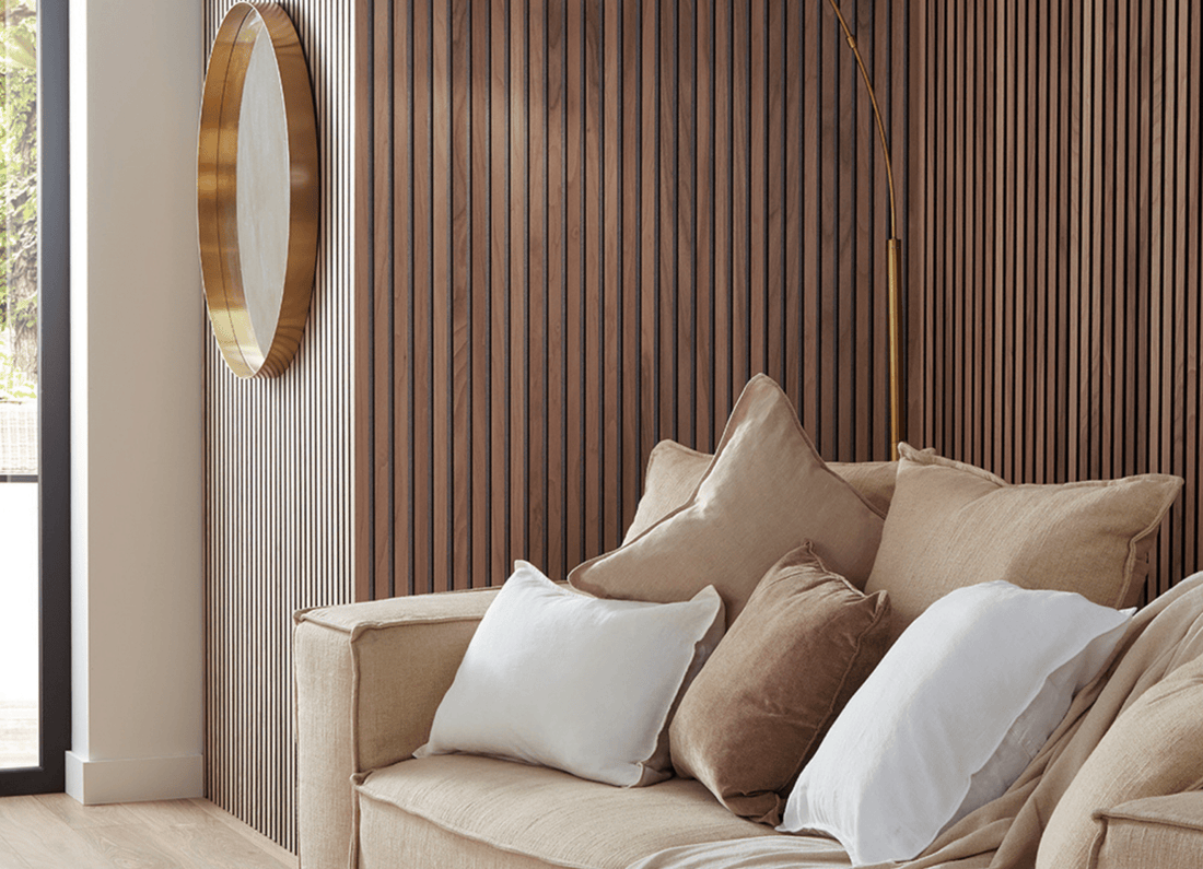 SlatWall Walnut wall panels in a room with a round gold mirror and a beige sofa with matching cushions