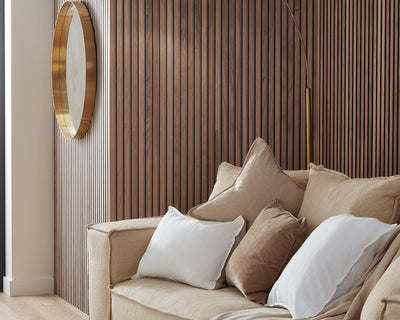 SlatWall Walnut wall panels in a room with a round gold mirror and a beige sofa with matching cushions