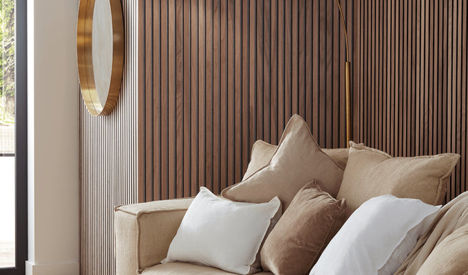 SlatWall Walnut wall panels in a room with a round gold mirror and a beige sofa with matching cushions