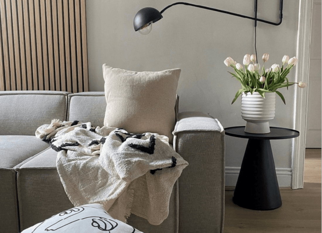 SlatWall behind a sofa with a black lamp and tulips in a vase