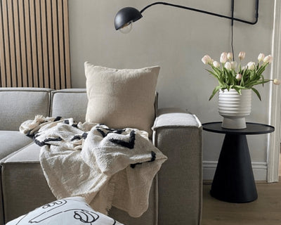 SlatWall behind a sofa with a black lamp and tulips in a vase
