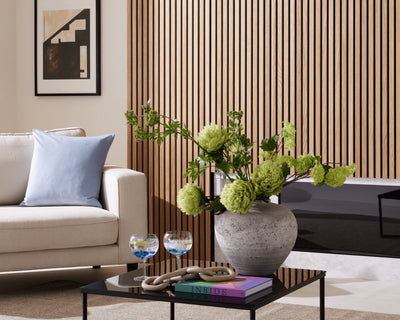 Summer décor idea featuring SlatWall Oiled Natural Oak, a white chair with blue cushion and a vase of green flowers.