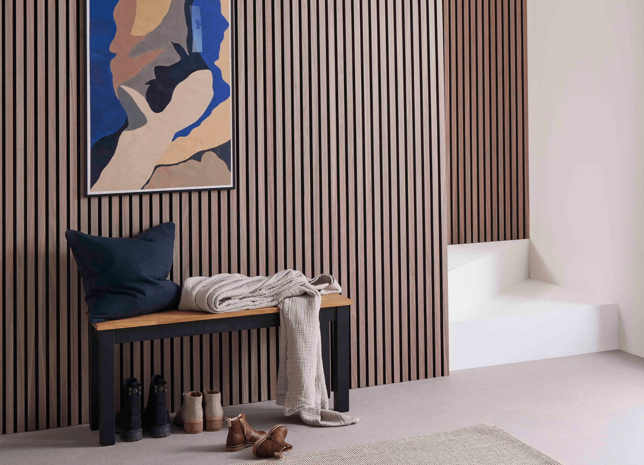 Hallway wall decorating idea featuring SlatWall Walnut wood veneer panels, a blue and beige painting and matching bench.