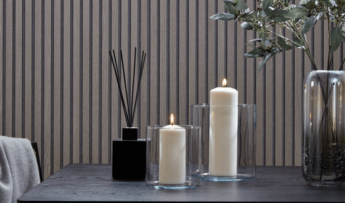 Greige interior design featuring SlatWall Grey Oak panels and a black table with two lit candles, a reed diffuser and vase
