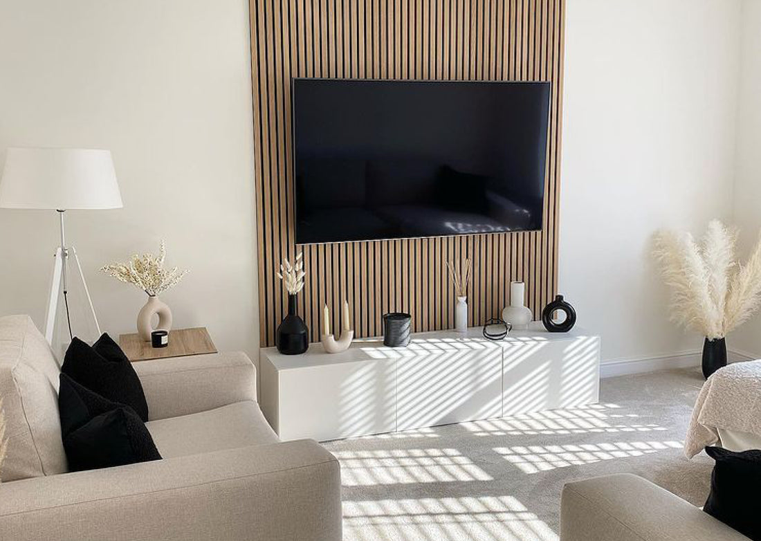 Light interior space with homely decor. Including a cream sofa, with black cushions, and a Naturewall SlatWall feature on the wall surrounding a TV.
