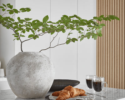 Large rounded stone vase on top of kitchen island with marble top.