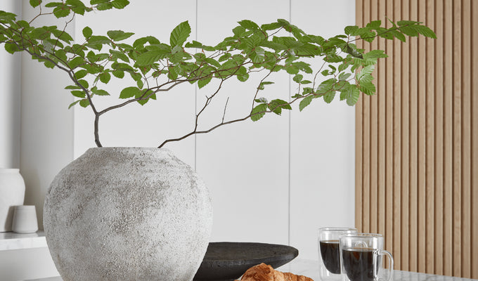 Large rounded stone vase on top of kitchen island with marble top.