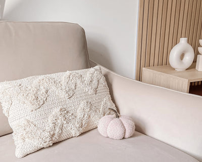 Small white pumpkin on a cream armchair. Slatwall wood panelling in the background