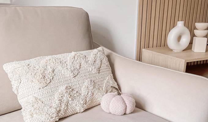 Small white pumpkin on a cream armchair. Slatwall wood panelling in the background