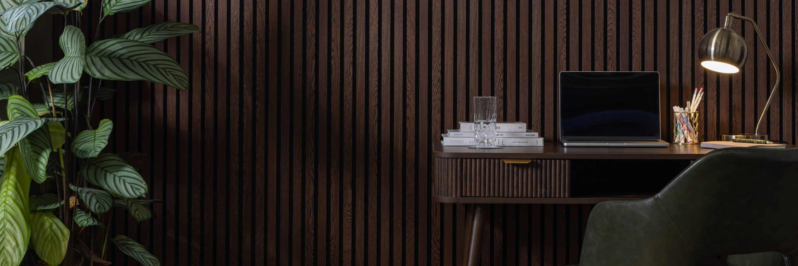 Modern office setup with a desk, laptop, and lamp against SlatWall Acoustic Wenge Slatted Wall Panel