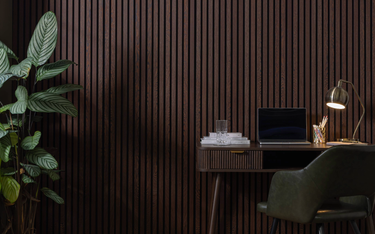 Modern office setup with a desk, laptop, and lamp against SlatWall Acoustic Wenge Slatted Wall Panel