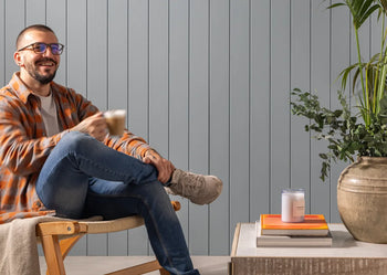 image of person sat infront of mdf panelling with a cup of coffee 