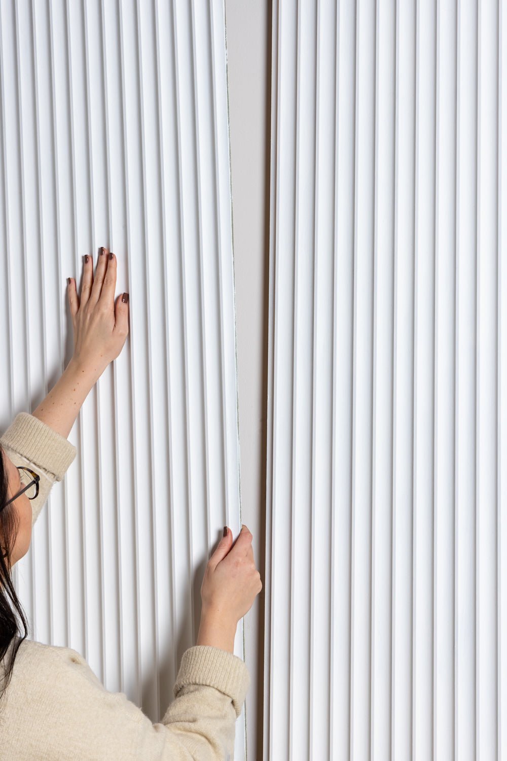 person placing primed Fluted MDF panel on wall

