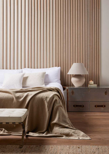 Washed Oak Individual slats on wall behind a bed with cream blanket and white pillows. Slats gradually have smaller gaps between. 