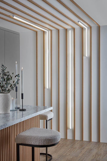 Waterproof individual slats spaced out on a kitchen wall with strip lighting between.

