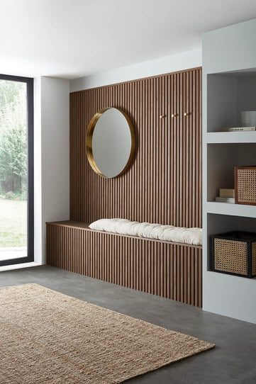 Room set imagery using SlatWall Waterproof in Walnut finish on a wall and small bench seating area. Large round mirror on the wall.