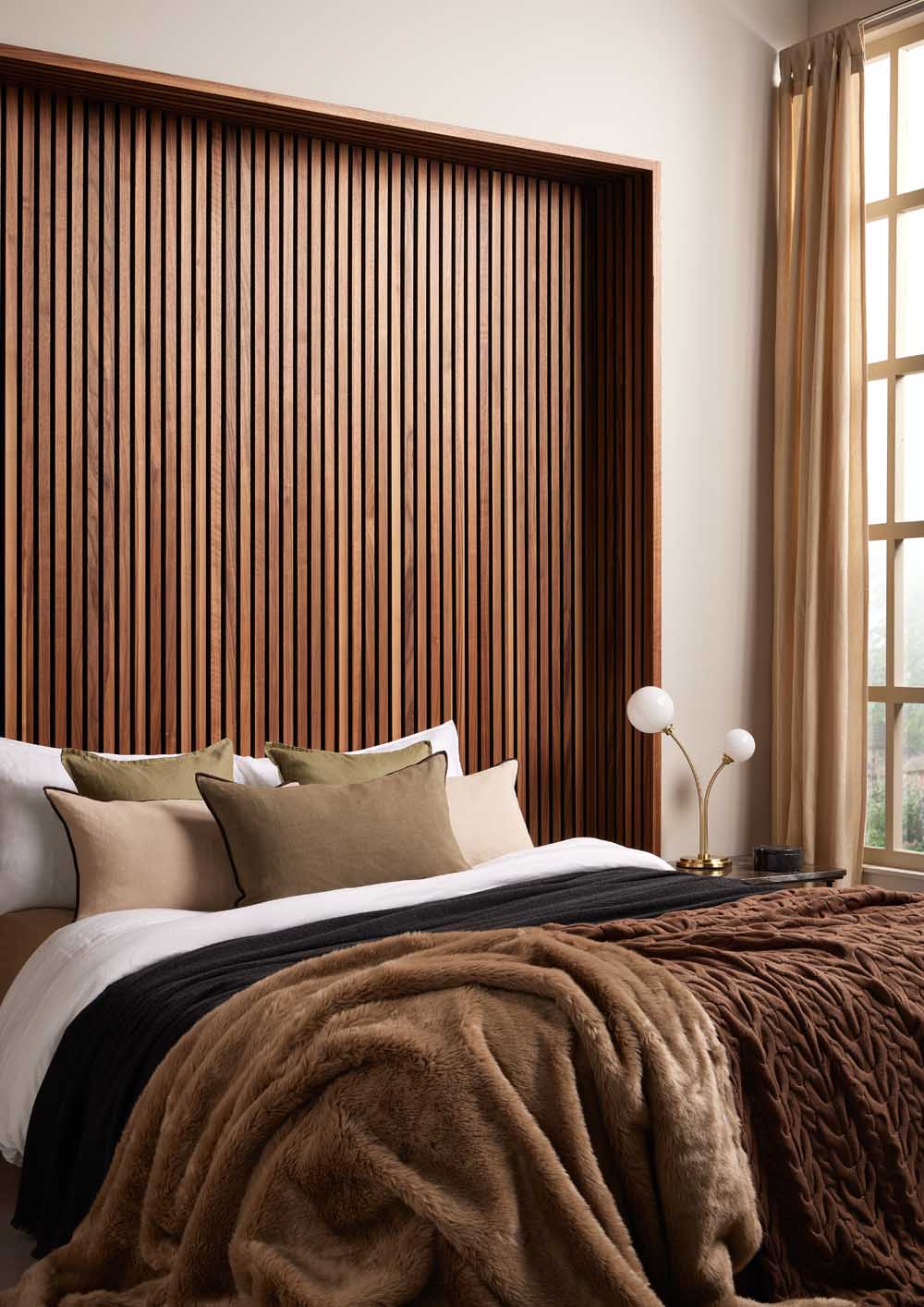 Room set image showing SlatWall Deep Walnut on black felt  behind a bed with cushions and blankets