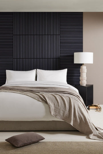 SlatWall Mini in charcoal black in linear layout behind a bed with neutral coloured bedding

